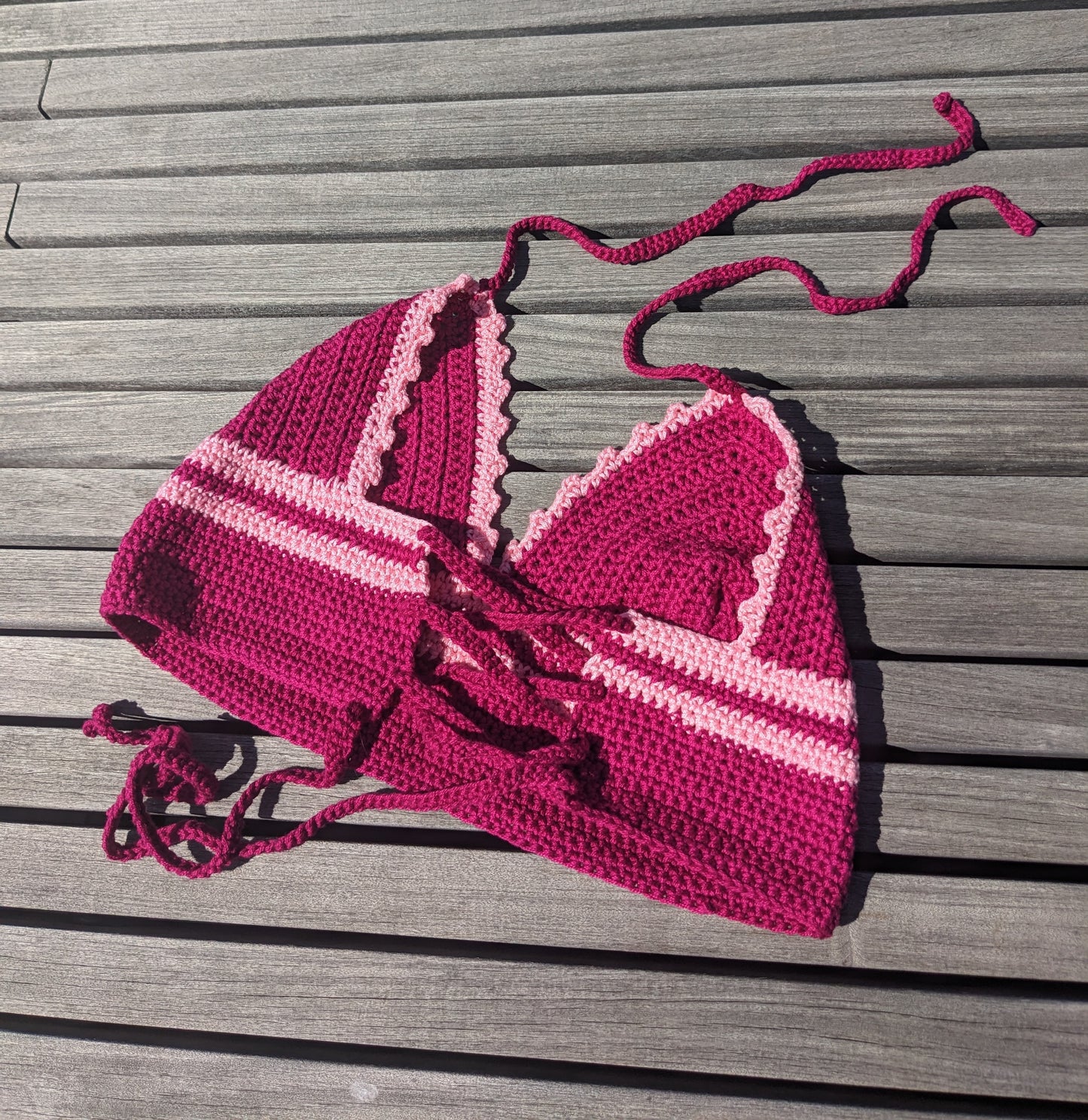 Detail of the surena crochet croptop in fuschia and pink, laid flat. Perfect summery top handmade with cotton yarn.