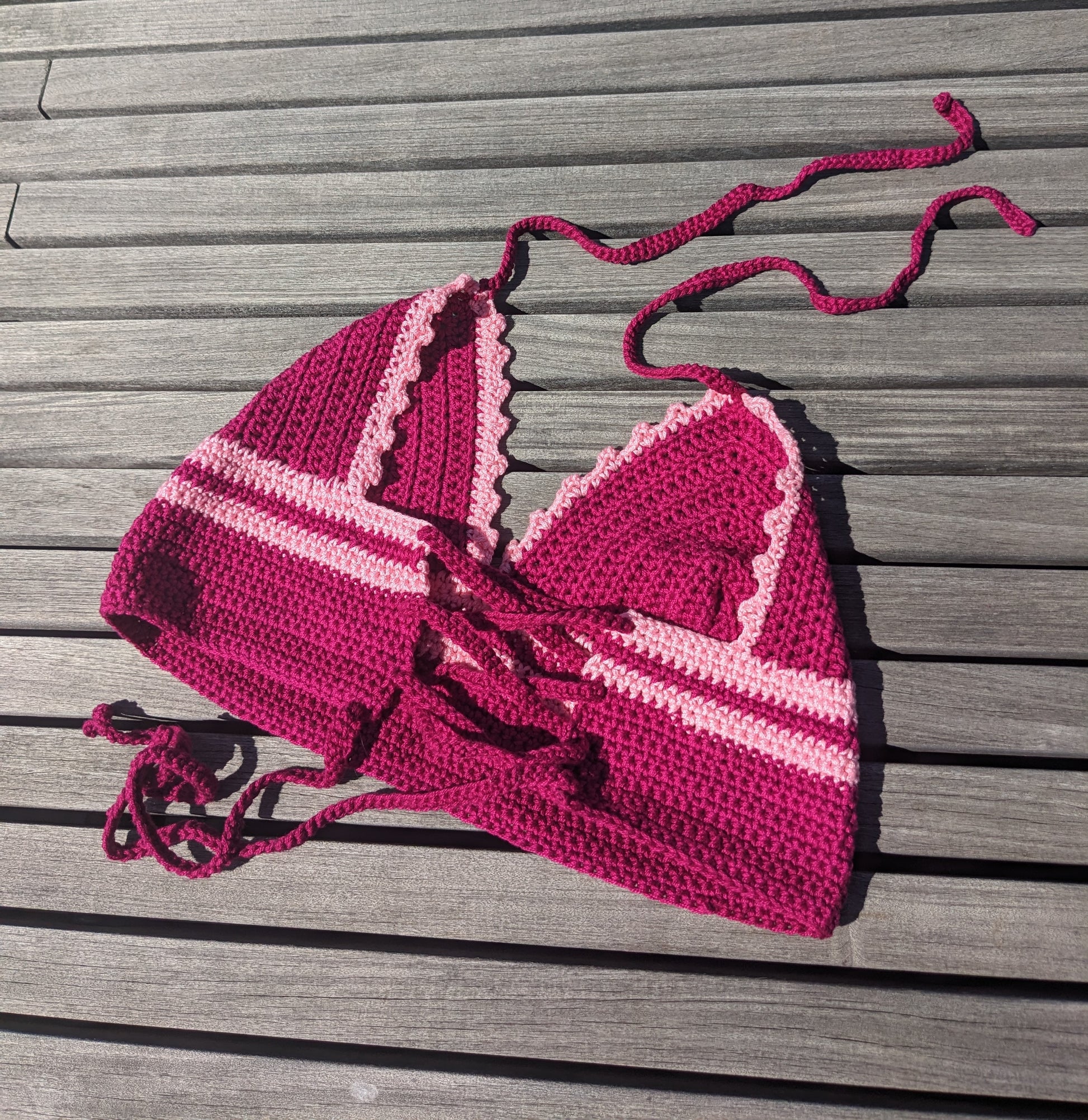 Detail of the surena crochet croptop in fuschia and pink, laid flat. Perfect summery top handmade with cotton yarn.