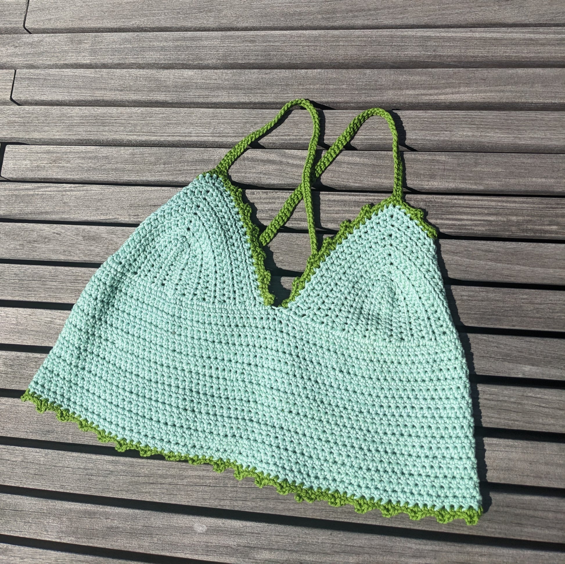 Detail of the surena crochet croptop in mint and green, paid flat. Handmade with cotton yarn, a perfect summery croptop