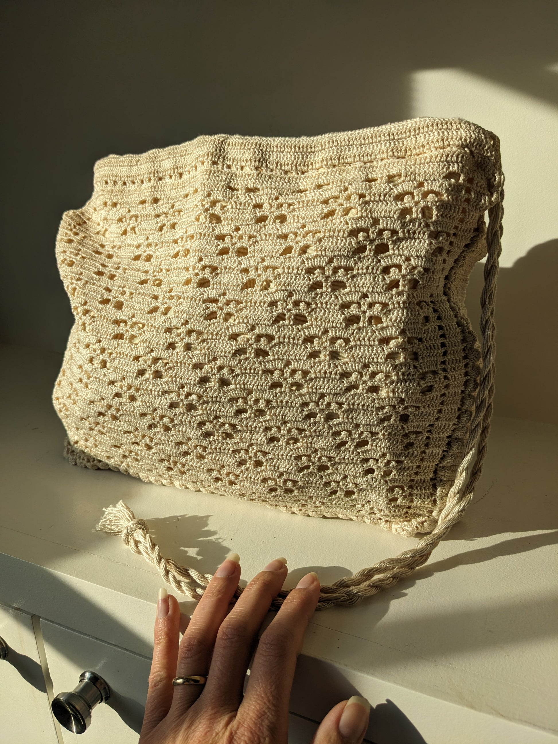 Beige crochet bag laid flat on white surface
