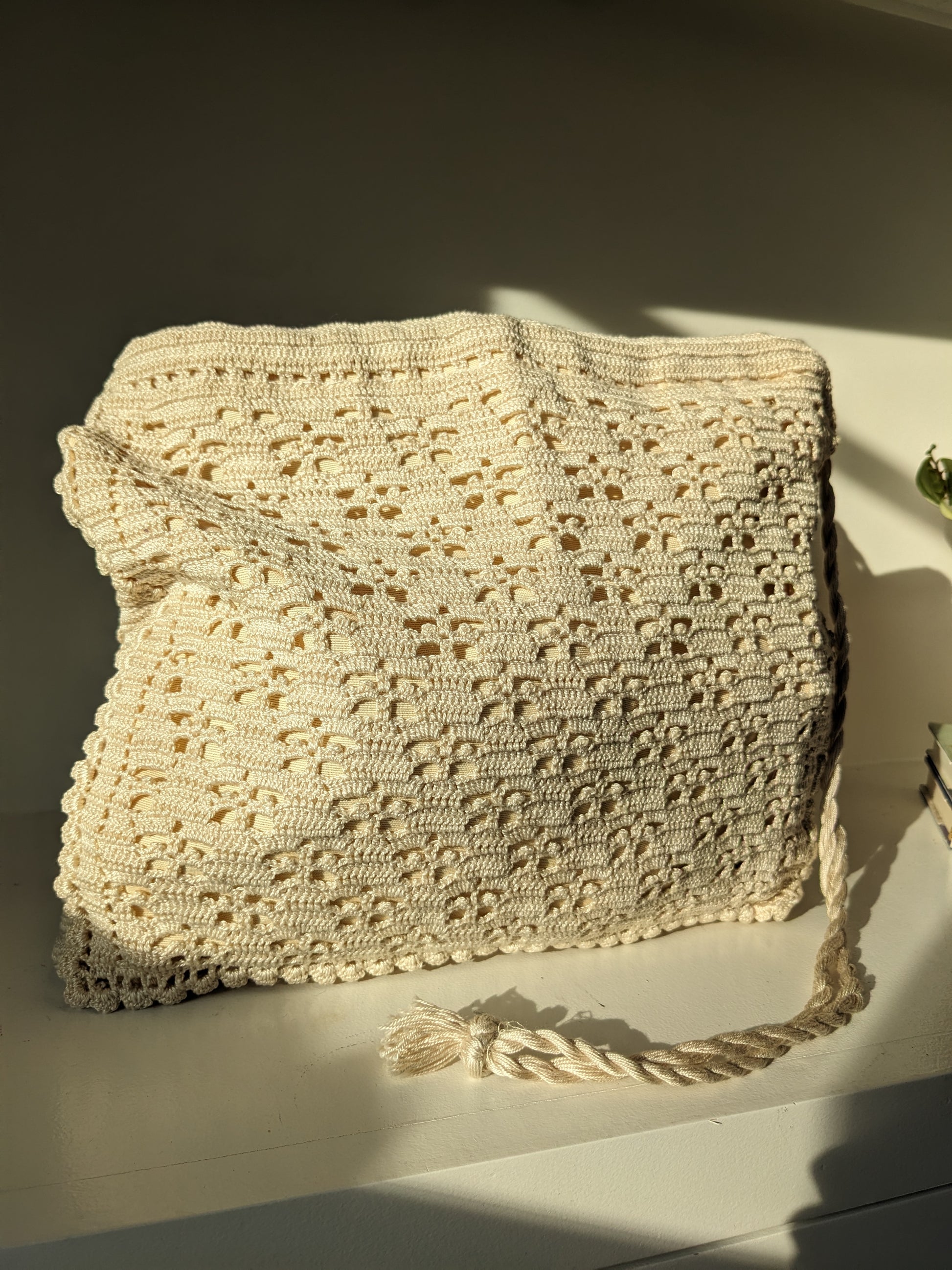 Beige crochet bag laid flat on white surface
