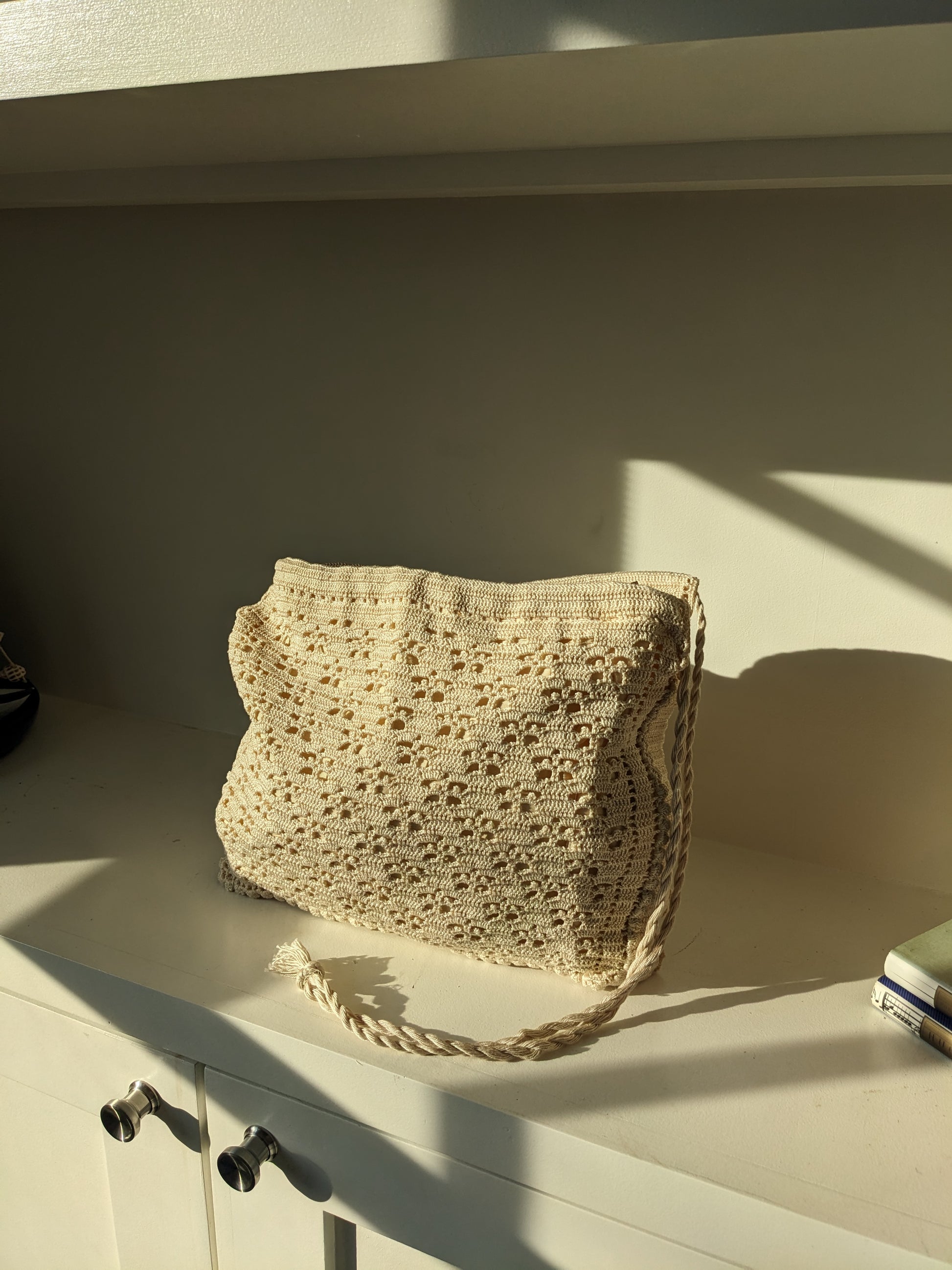 Beige crochet bag laid flat on white surface