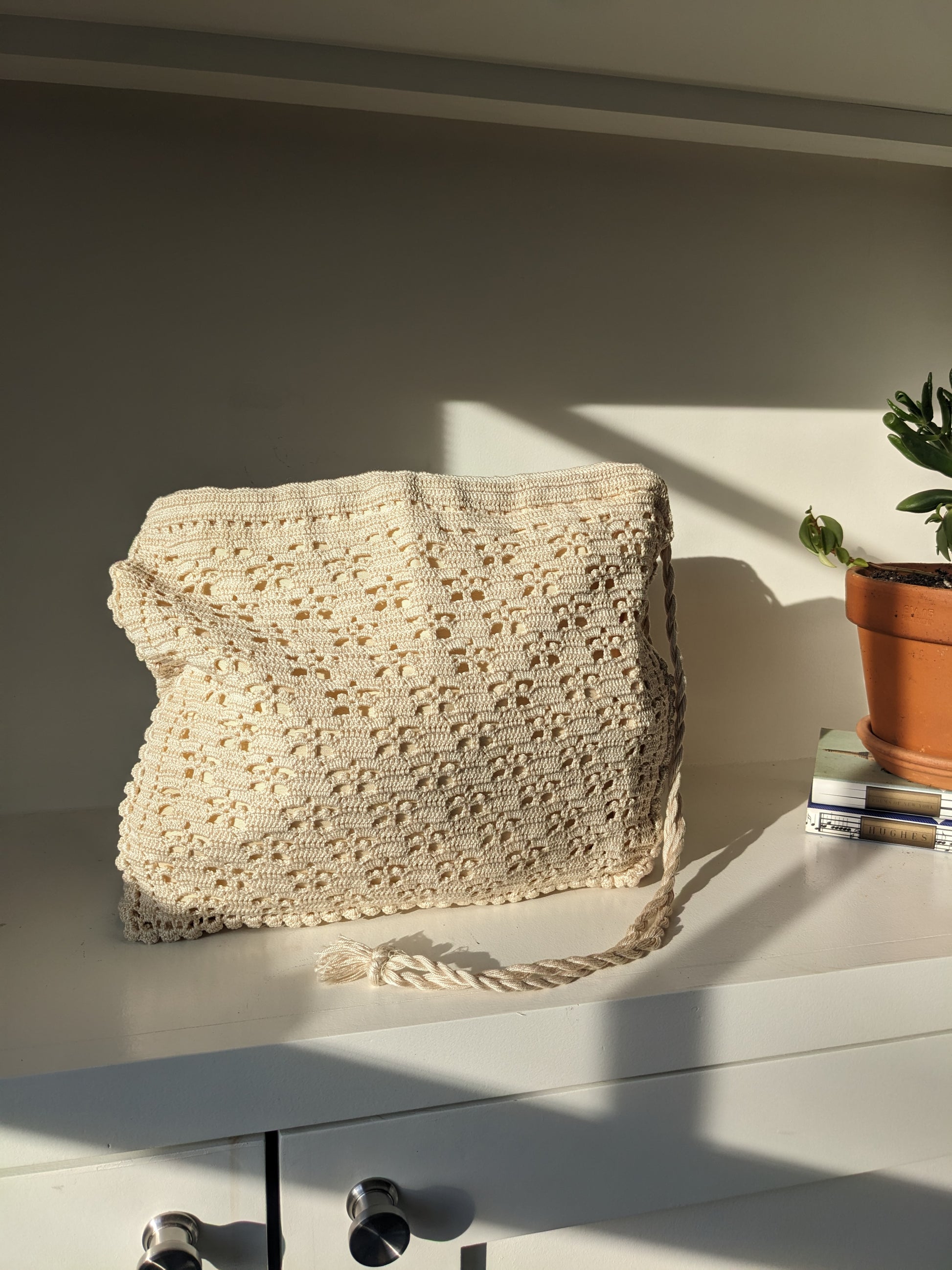 Beige crochet bag laid flat on white surface