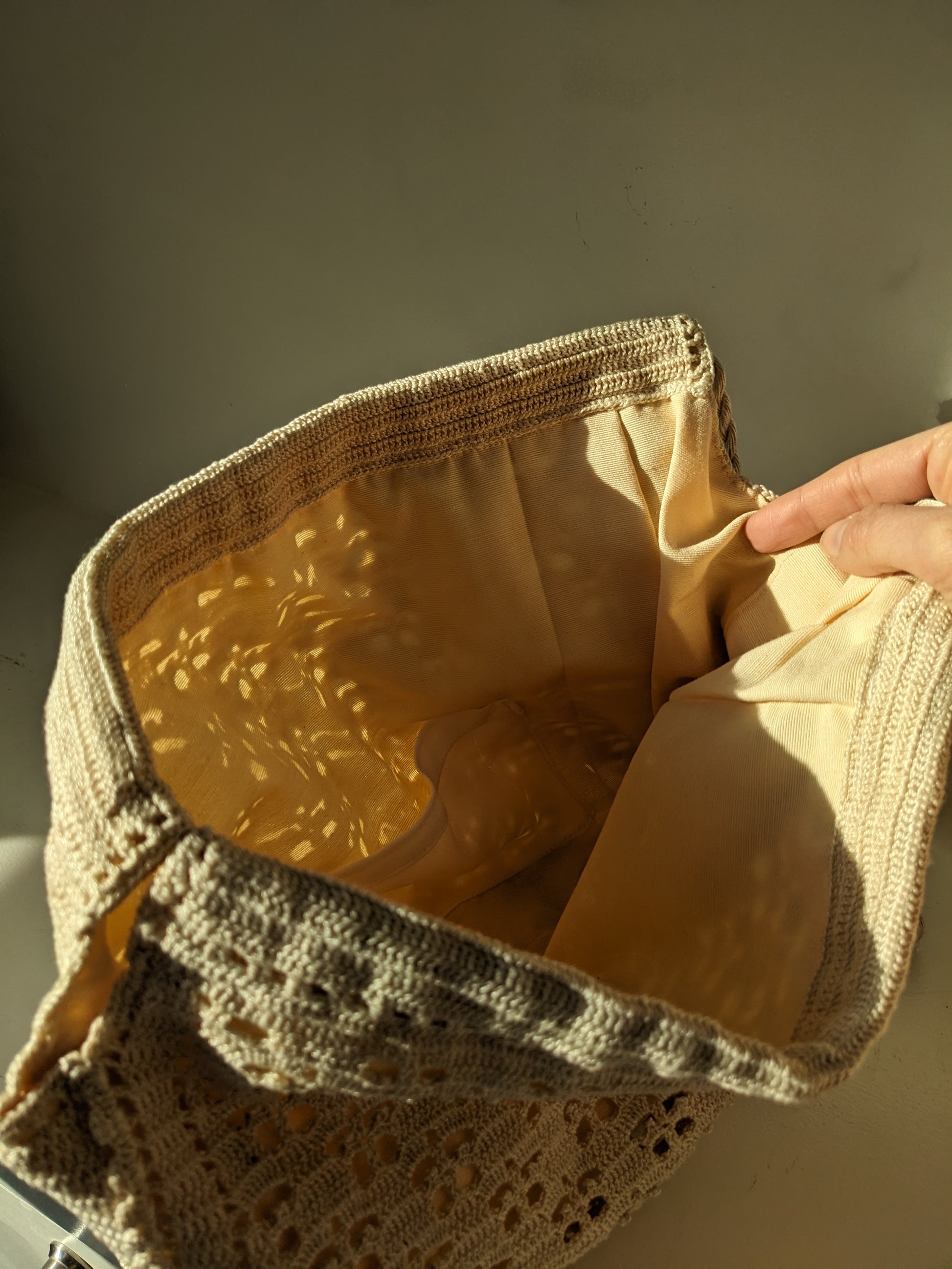 Beige crochet bag laid flat on white surface
