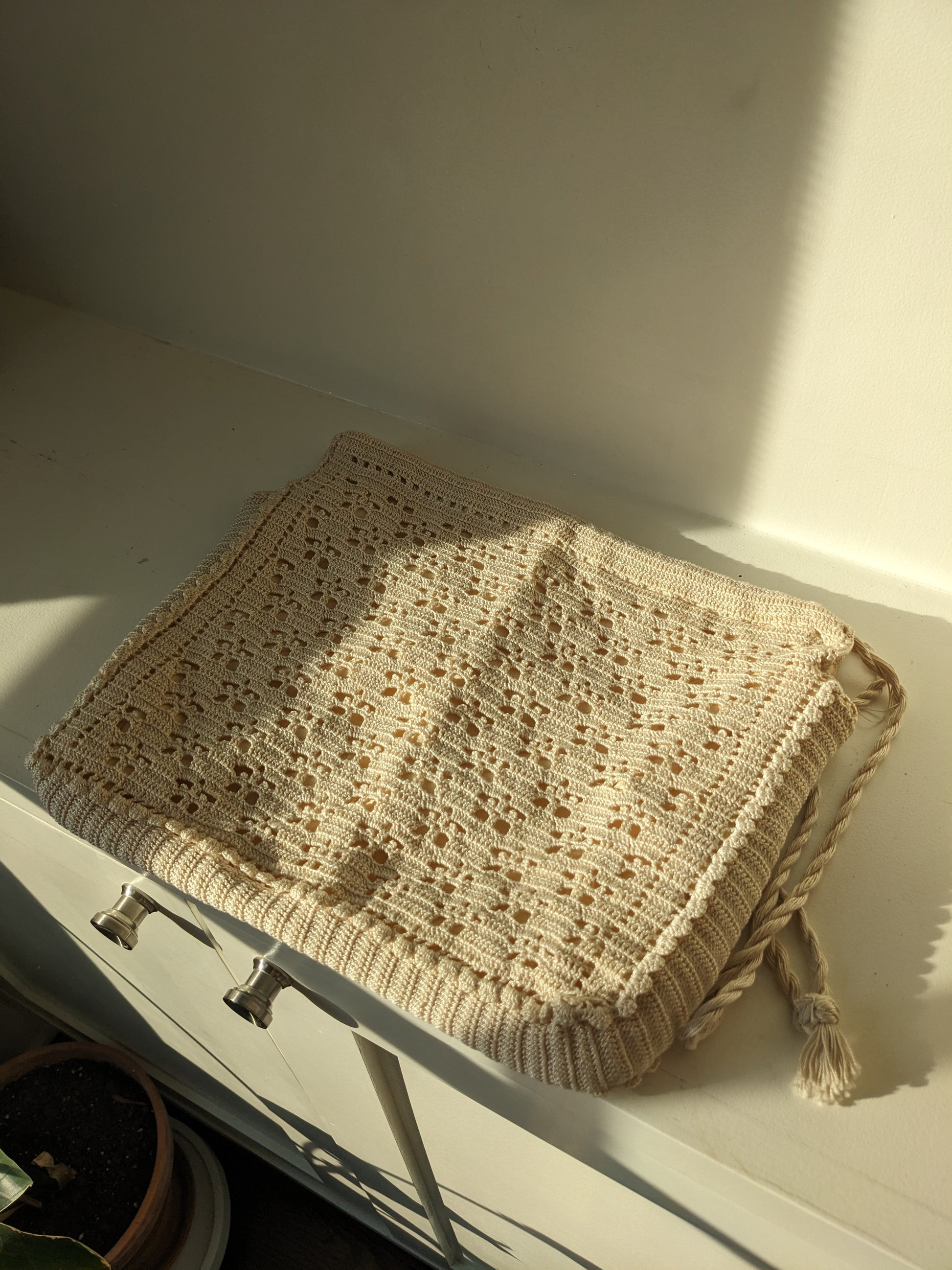 Beige crochet bag laid flat on white surface