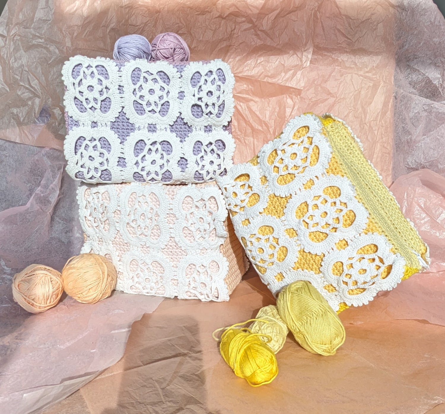 Three crochet upcycled bags with lace patterns and yarn balls behind a textured surface