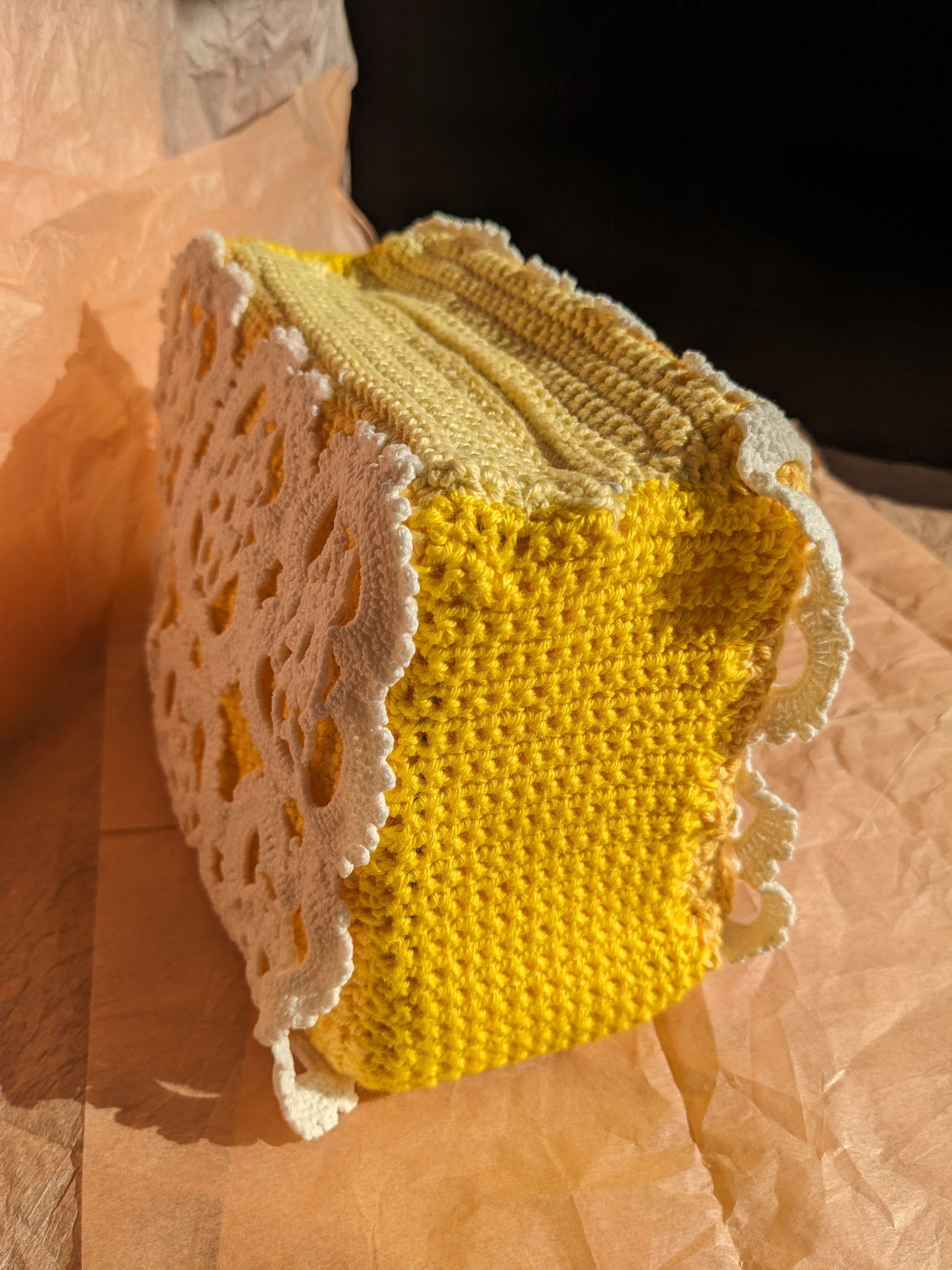 Crocheted yellow and beige upcycled vanity bag with lace trim on a textured surface