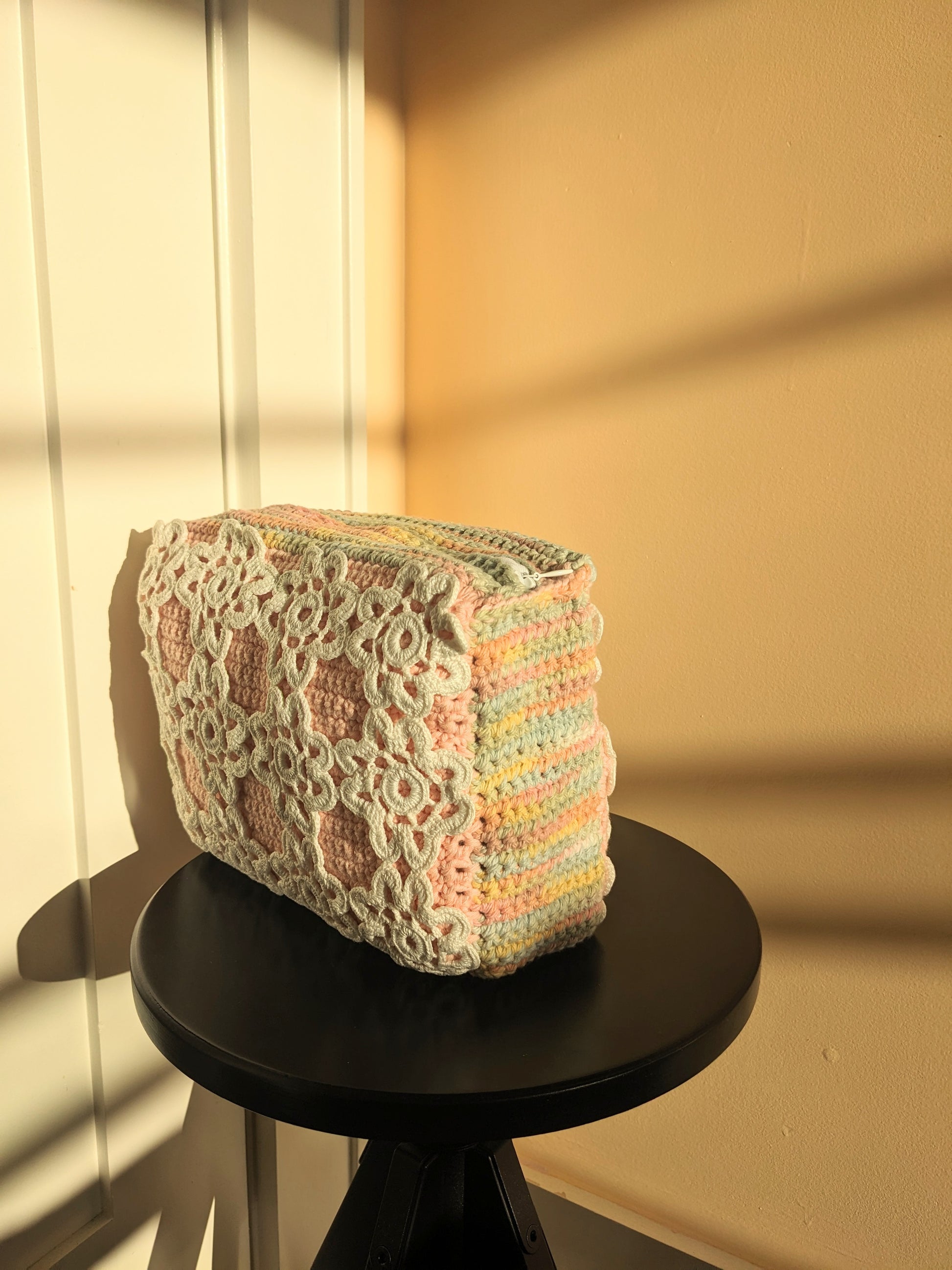 Upcycled crochet clutch on a stool against a white and salmon wall