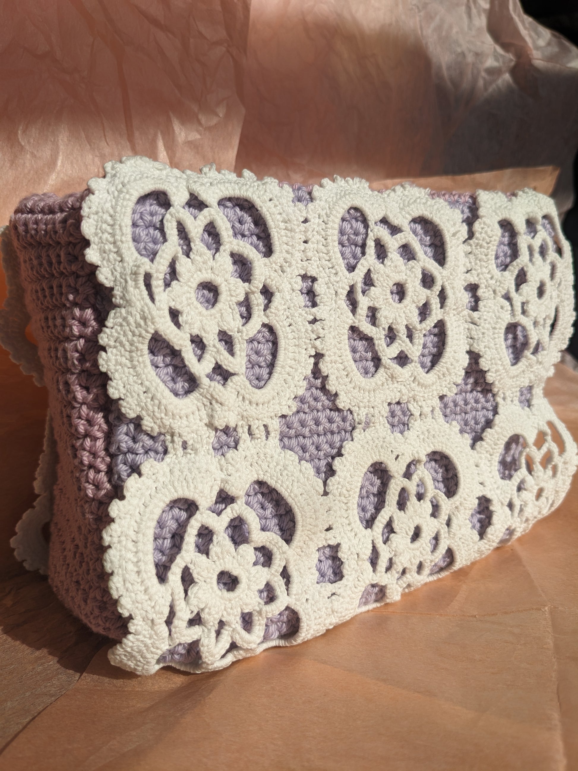 Upcycled crocheted vanity bag with a floral pattern on a textured pink surface