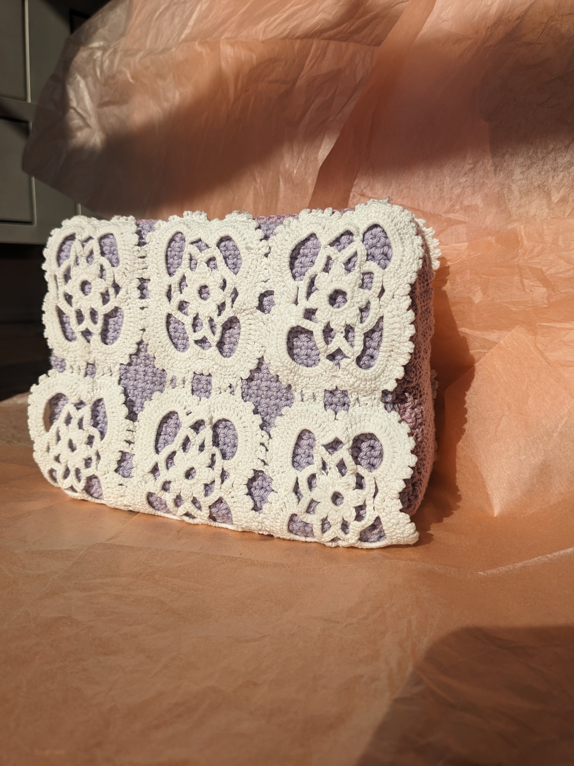 Upcycled crochet vanity bag on a pink surface