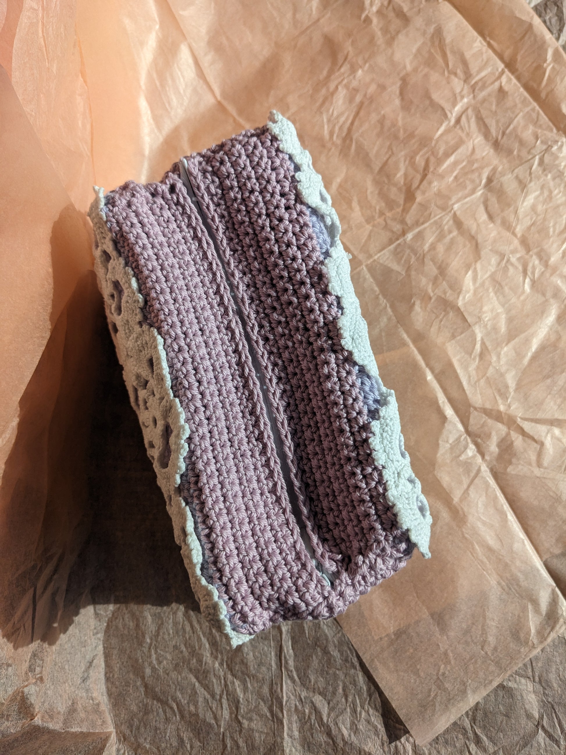 Upcycled crochet lilac vanity bag on a pink textured background