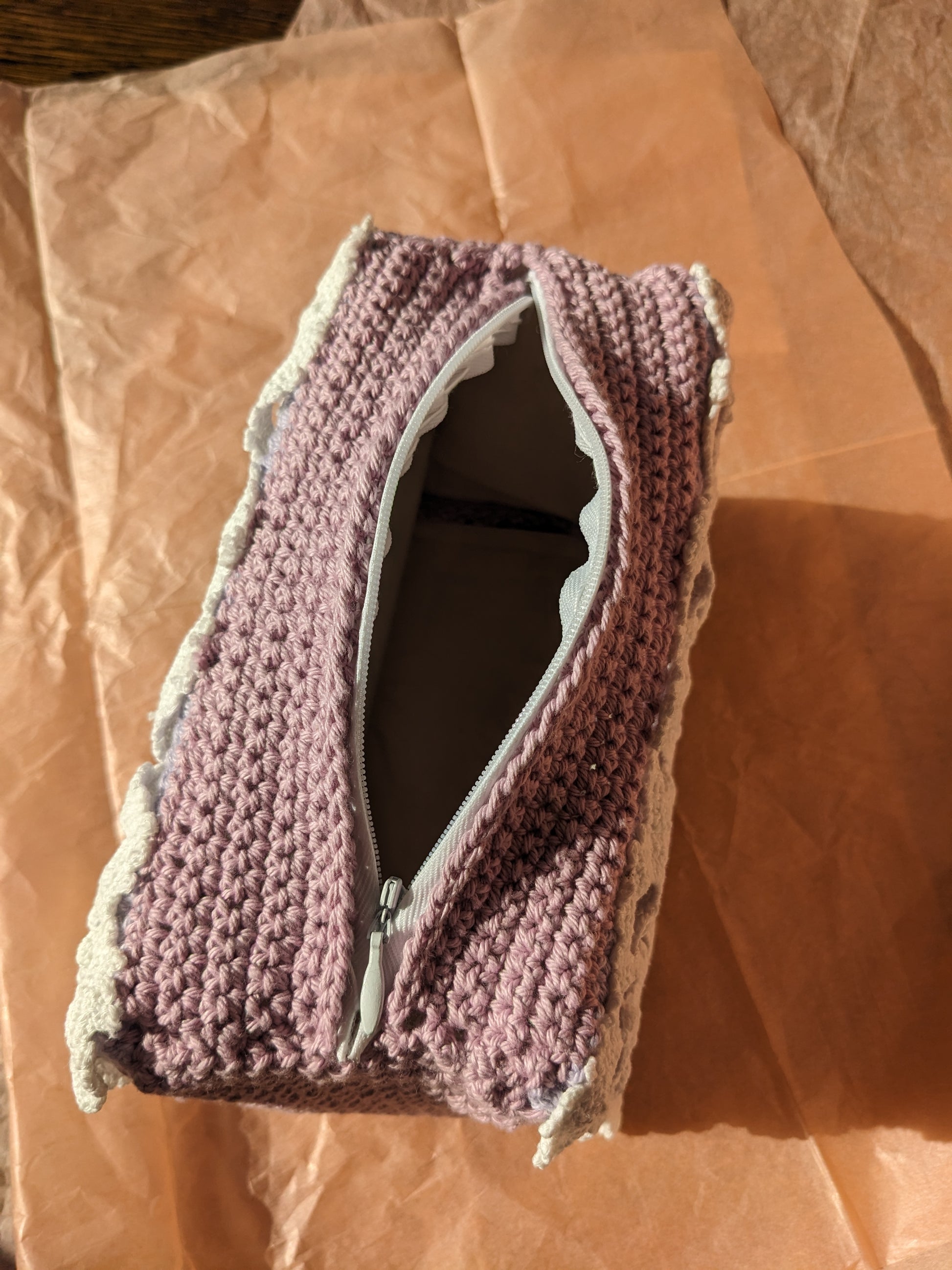 Upcycled crochet vanity bag with a zipper on a pink paper background