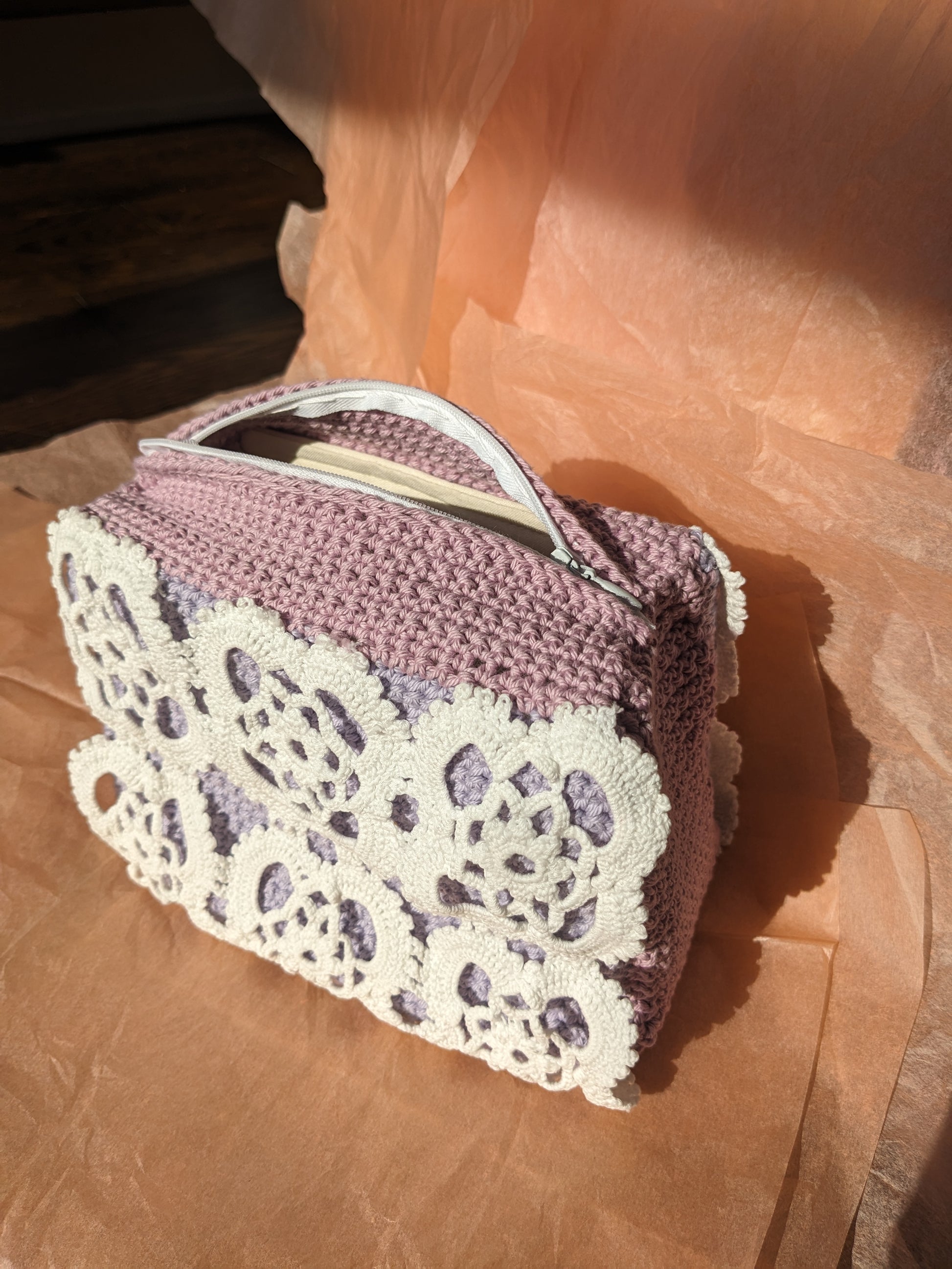 Upcycled crochet vanity bag against pink background