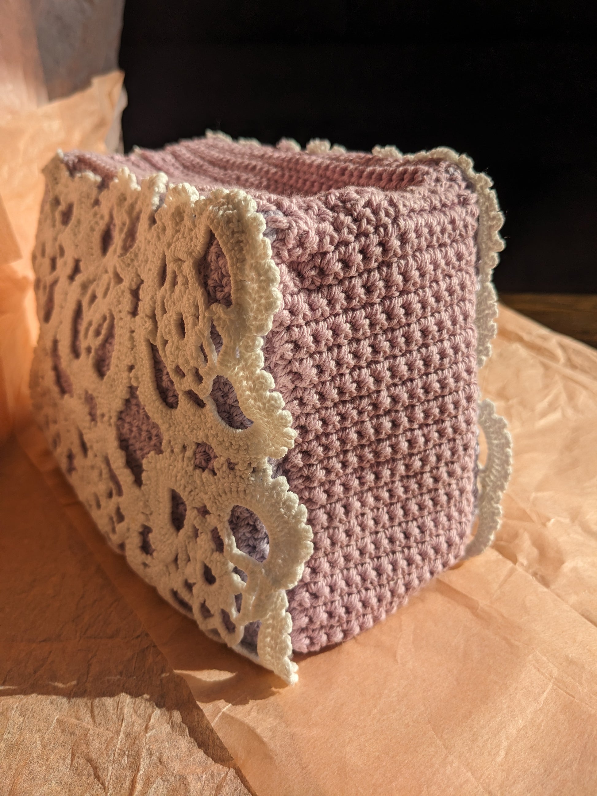 Lilac upcycled crochet vanity bag on a pink surface
