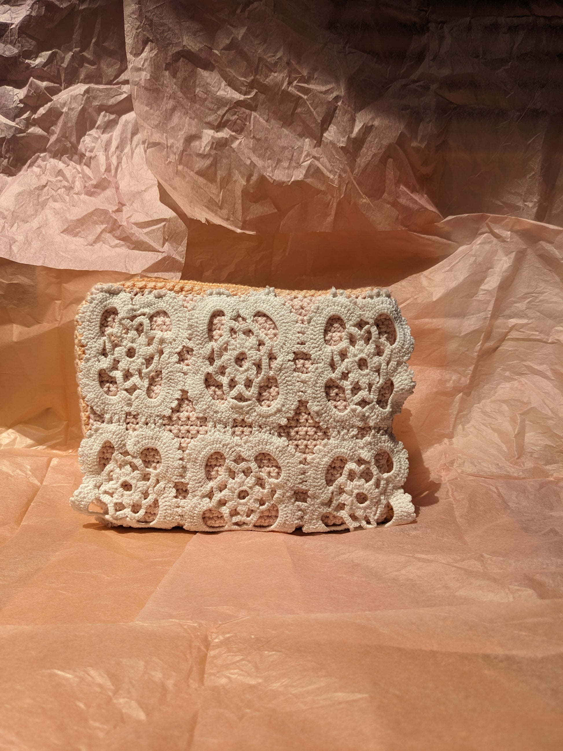 Upcycled crochet vanity bag on a textured pink surface