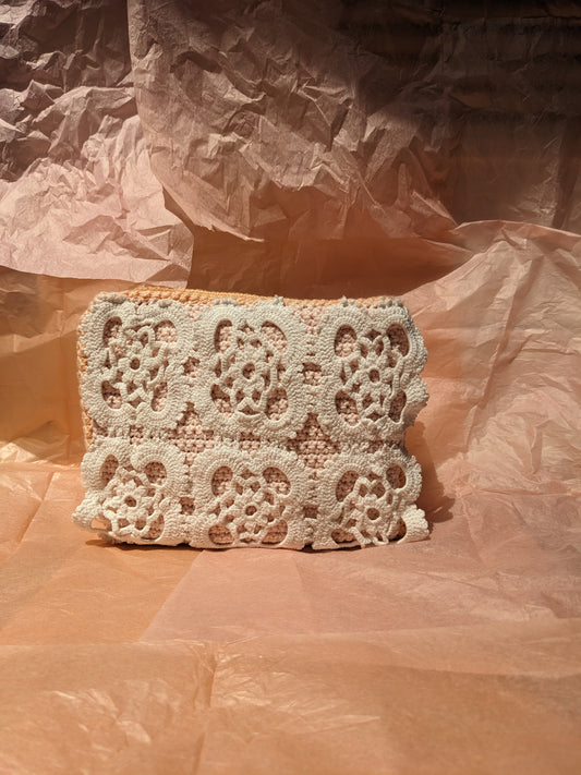 Upcycled crochet vanity bag on a textured pink surface