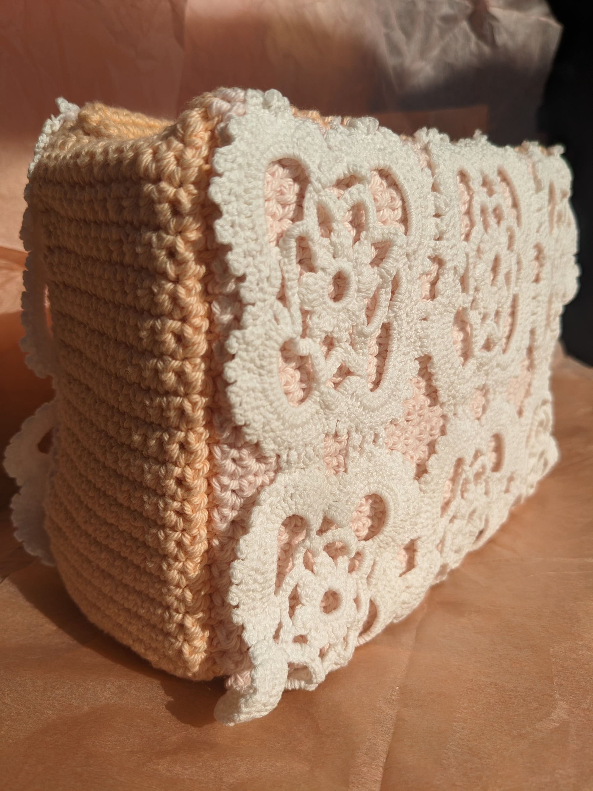 Upcycled crocheted vanity bag on a textured pink surface