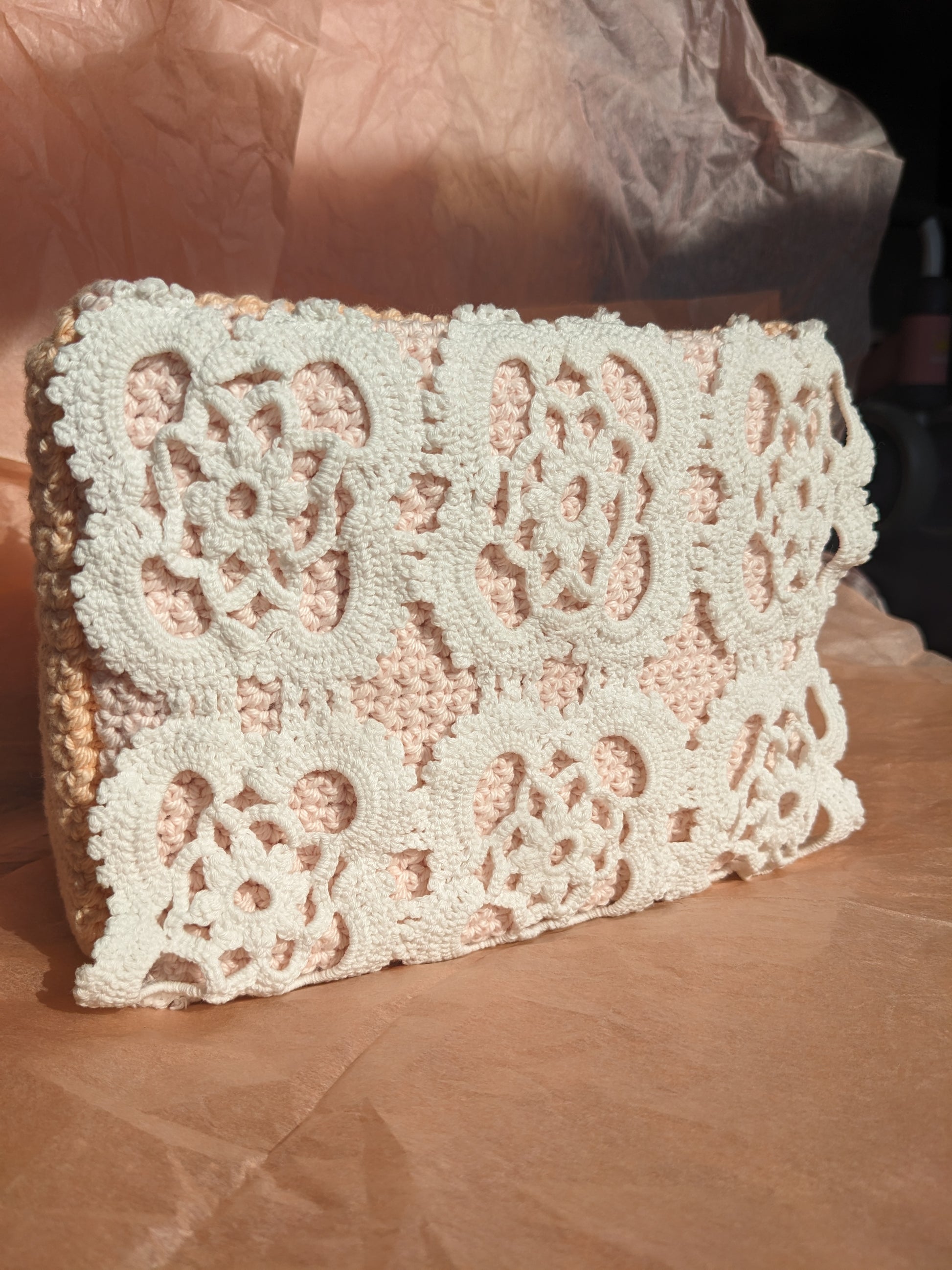 Upcycled crochet vanity bag on a pink textured background