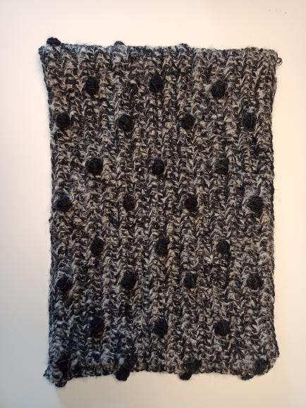 Detail of the surena crochet Pecas cowl in grey and black.