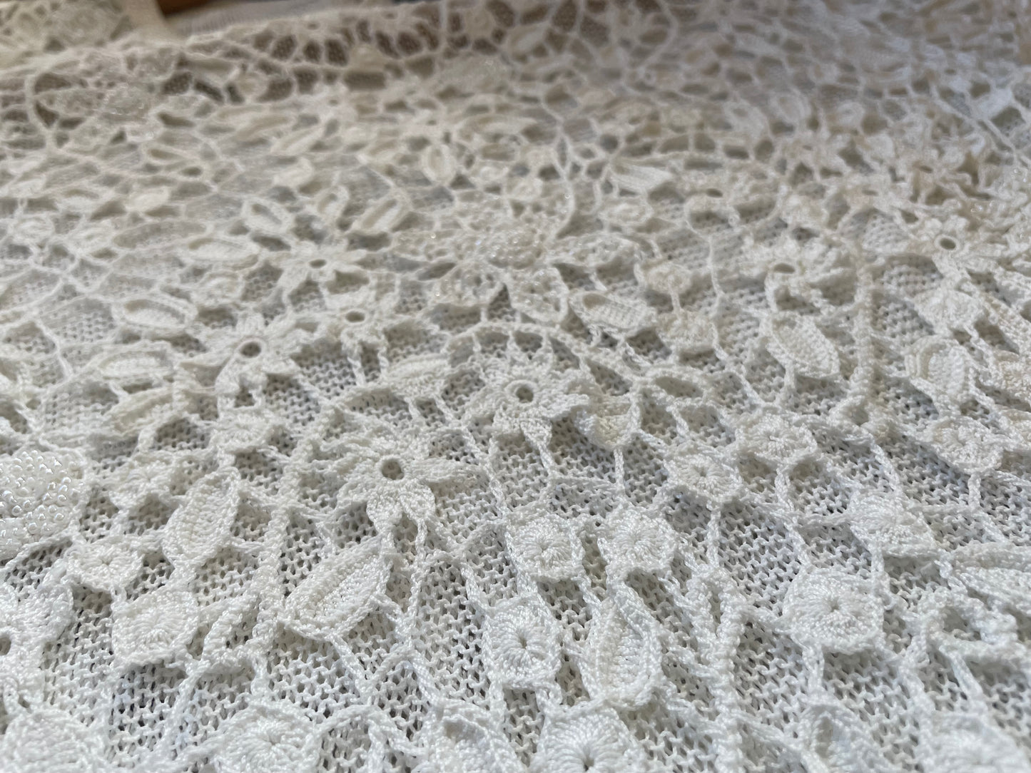 Detail photo of the white crochet beaded shirt, showing the flower crochet pattern