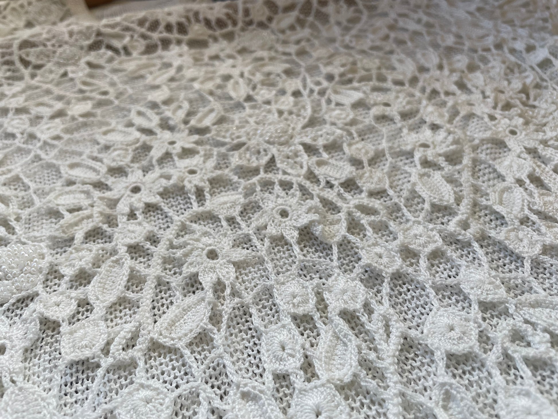 Detail photo of the white crochet beaded shirt, showing the flower crochet pattern
