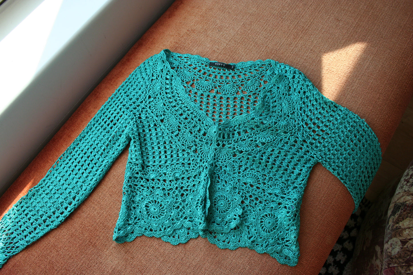 Boho turquoise crochet vest laid flat on the couch