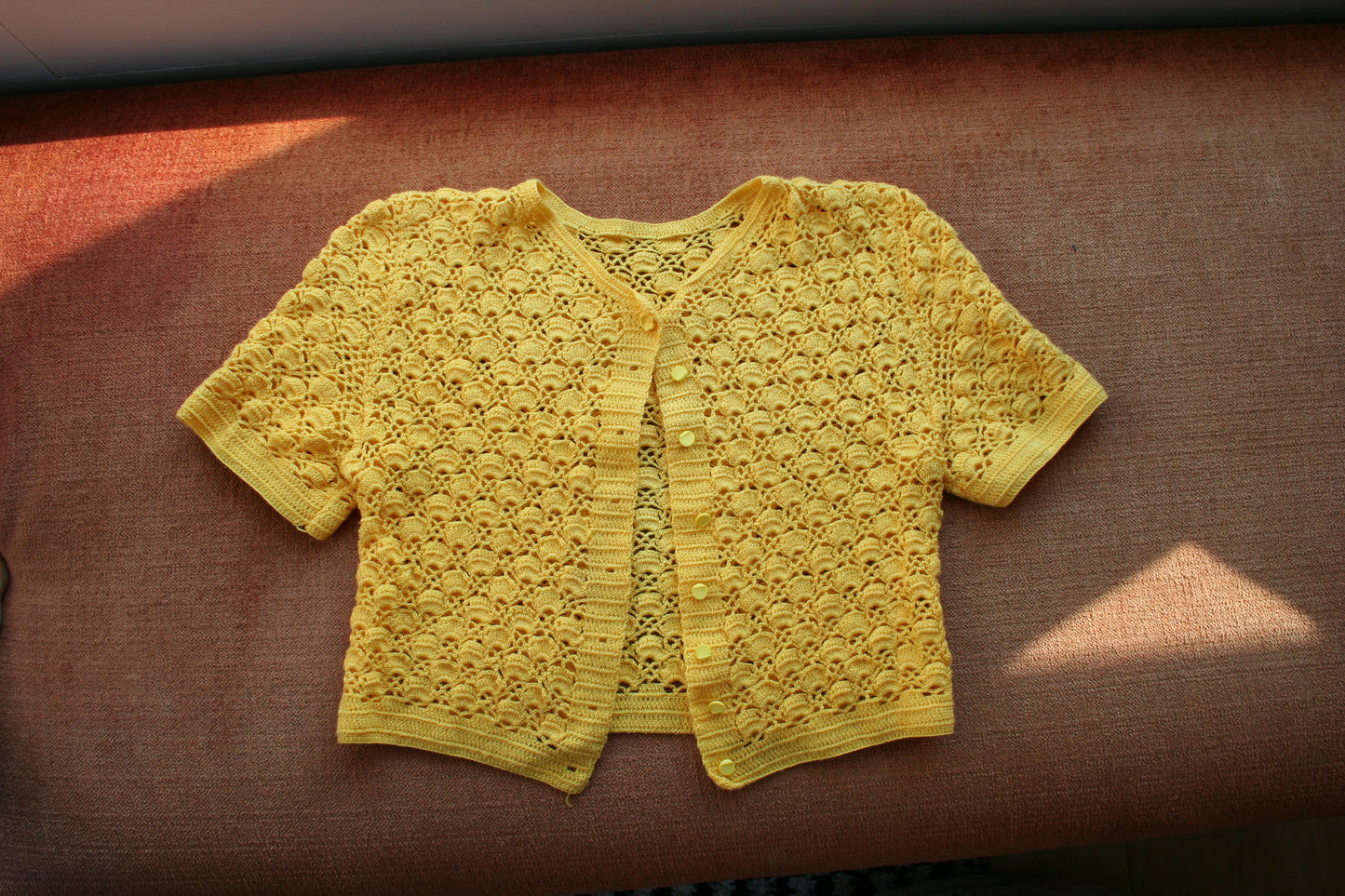 Sunshine yellow crochet cardigan laid flat