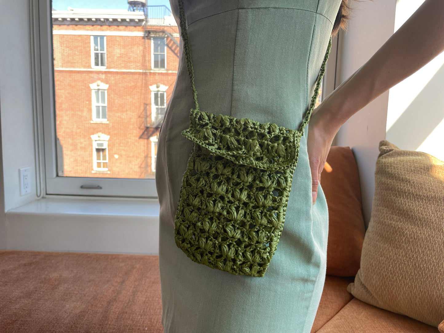 Model wearing the crossbody raffia bag in dark green