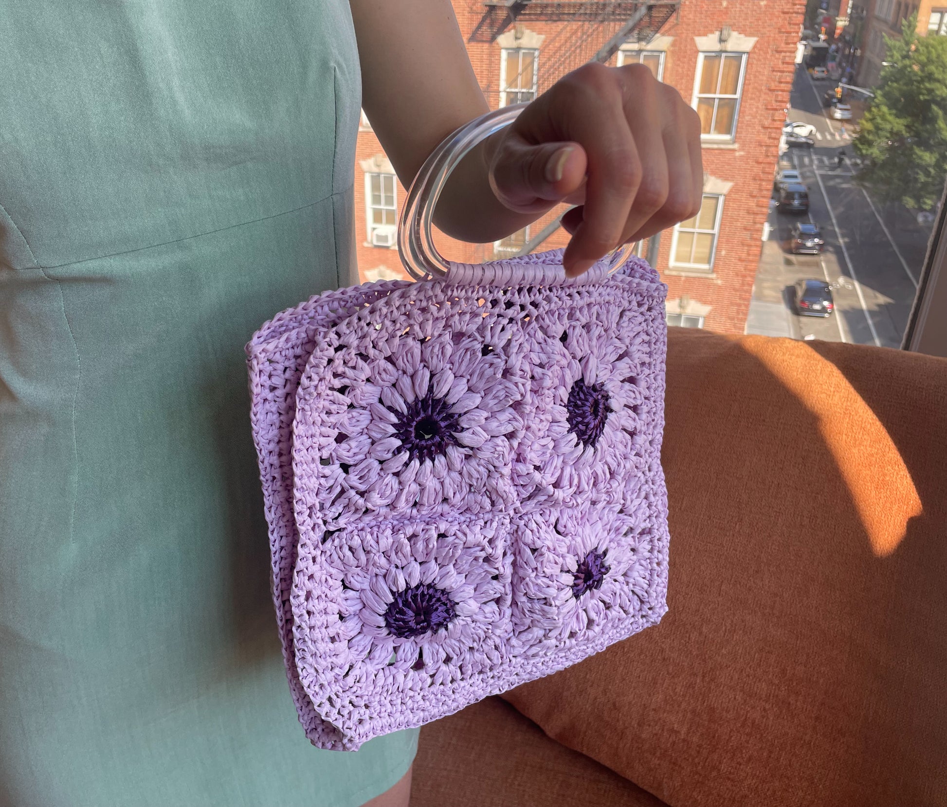 Model wearing the Granny square frame bag made in purple and lilac raffia.