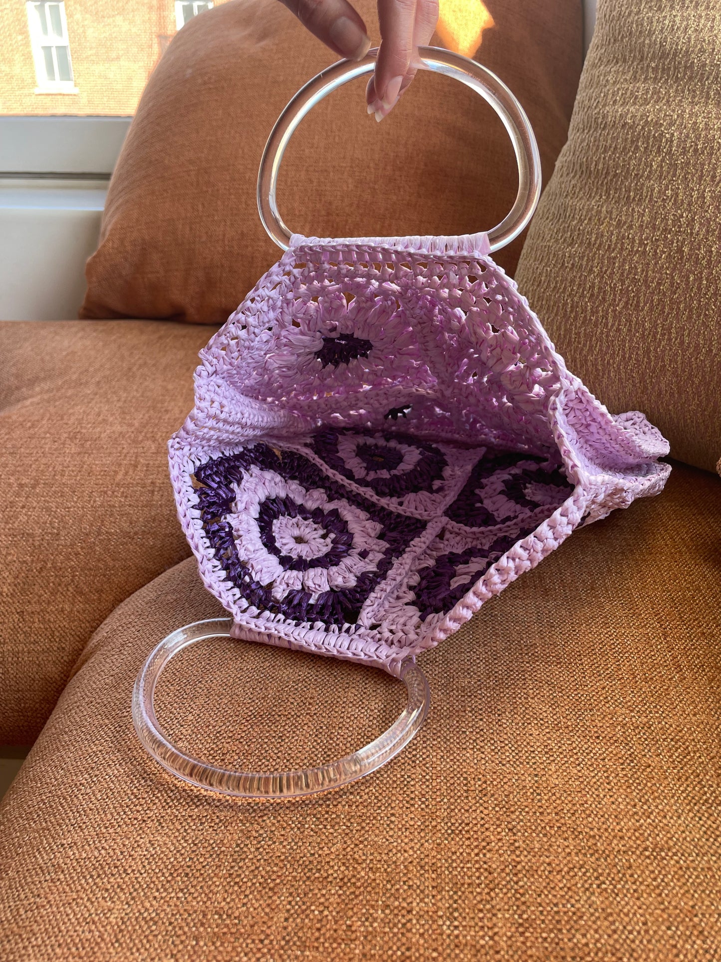 Model holding and showing the inside of the Granny Square raffia crochet bag