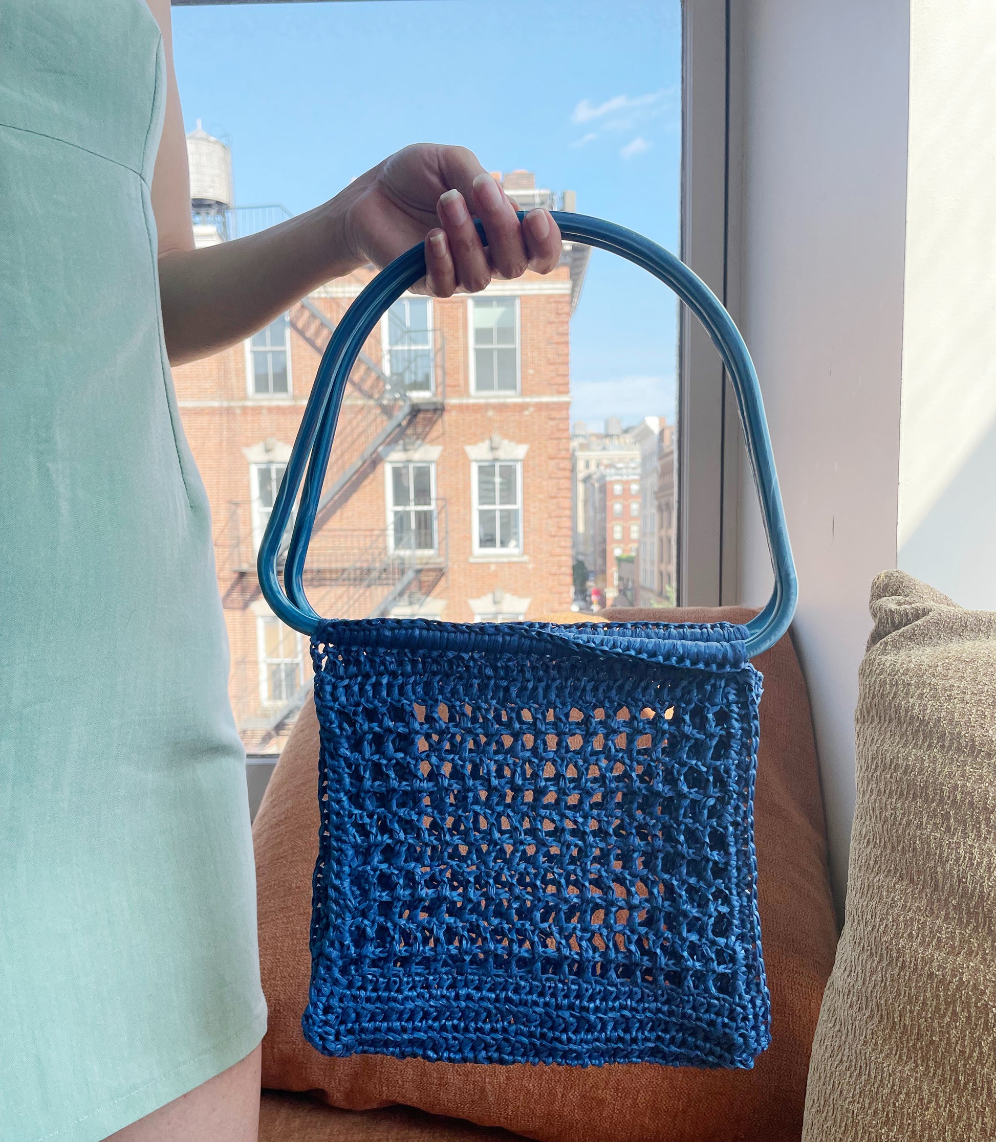 Model holding the market raffia bag in blue
