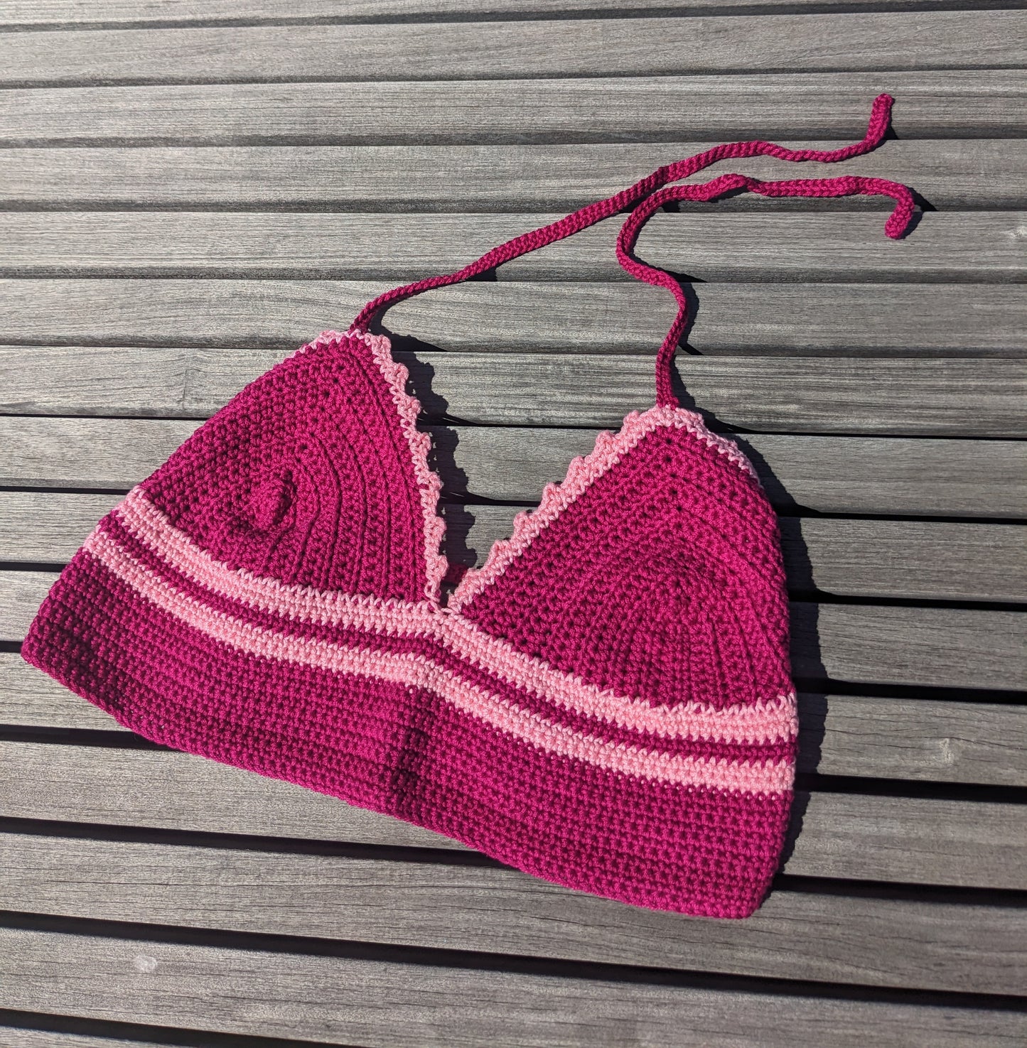 Surena crochet croptop handmade with fuchsia and pink cotton yarn, laid flat.