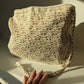 Beige crochet bag laid flat on white surface