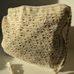 Beige crochet bag laid flat on white surface