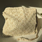 Beige crochet bag laid flat on white surface