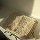 Beige crochet bag laid flat on white surface