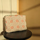 Pink and white lace clutch crochet bag on a black stool against a beige and salmon wall
