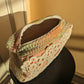 Multicolored crochet ucpcycled bag with lace detail on a black stool against a beige and salmon wall.