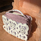 Upcycled crochet vanity bag against pink background