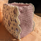 Lilac upcycled crochet vanity bag on a pink surface