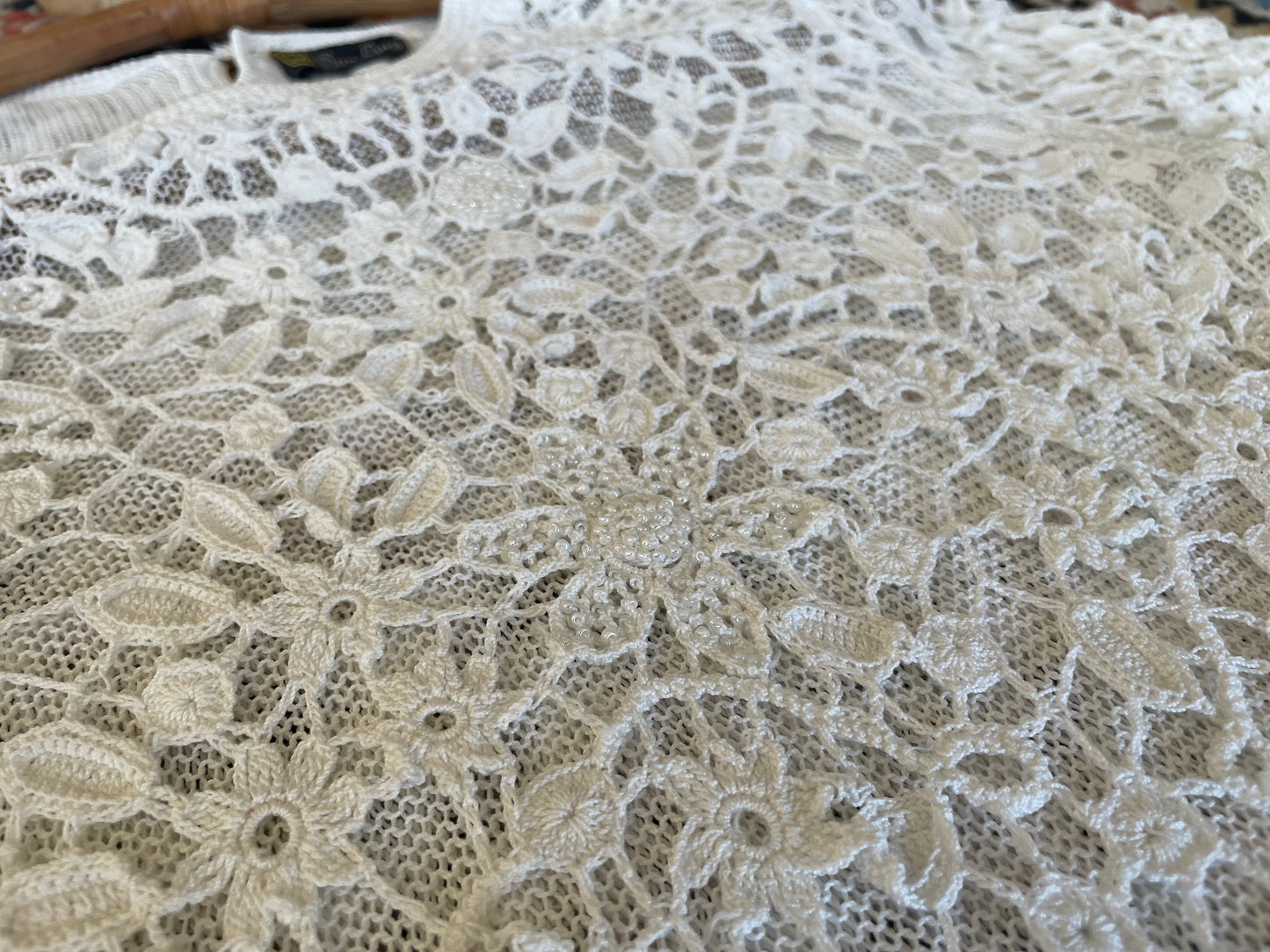 Detail photo of the white beaded shirt, showing the flower crochet pattern