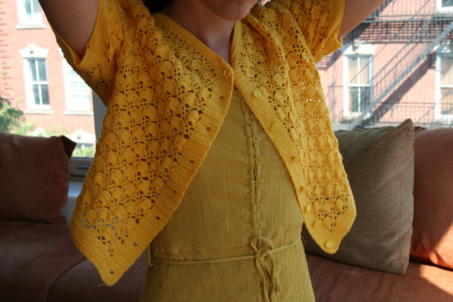 Model wearing the sunshine crochet cardigan, buttoned at the top