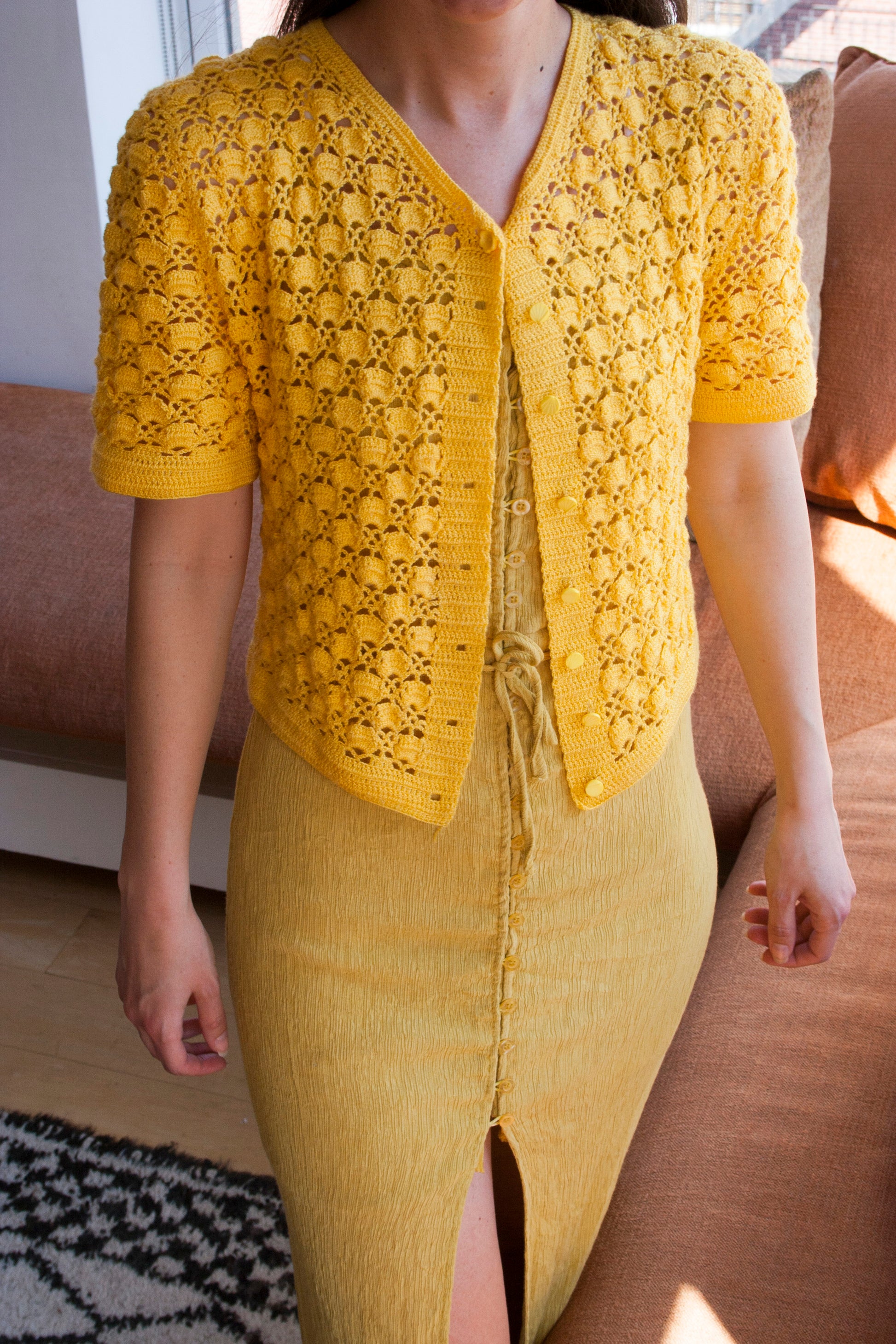 Model wearing the sunshine crochet cardigan, buttoned at the top