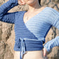 Model wearing the surena crochet ballerina wrap top in navy and baby blue, a handmade crochet top made with cotton yarn.