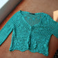 Boho turquoise crochet vest laid flat on the couch 