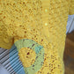 Detail on small blemish on the surena crochet "preloved" collection yellow sunshine cardigan.