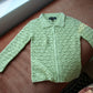 Green flower garden crochet cardigan laid flat on a couch
