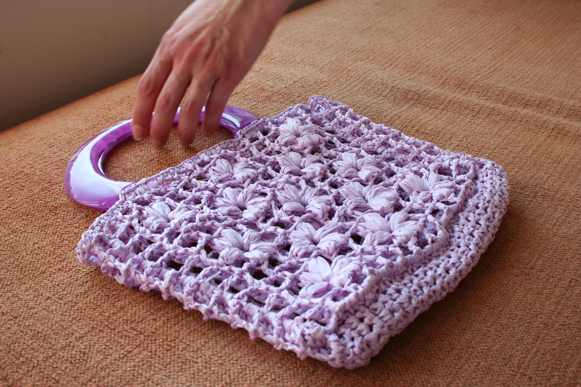 Model's hand about to hold the jazmín crochet raffia bag 