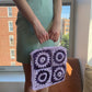Model wearing the Granny square frame bag made in purple and lilac raffia. 