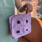Model wearing the Granny square frame bag made in purple and lilac raffia. 
